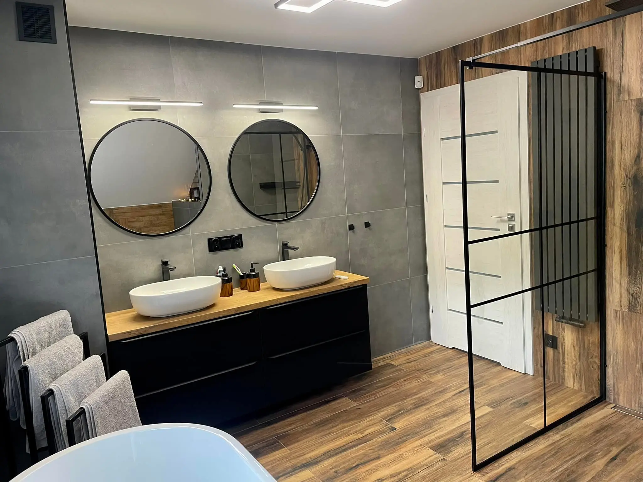 Nowoczesna łazienka z dwiema nablatowymi umywalkami, podświetlanymi lustrami i drewnopodobną glazurą - realizacja REM-BUD Gdańsk