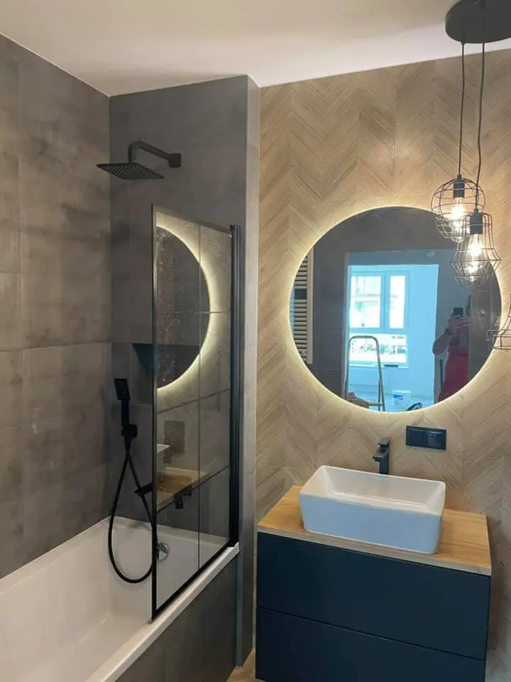 Stylowa łazienka z prysznicem, płytki układane w jodełkę i okrągłe podświetlane lustro - remonty łazienek Sopot